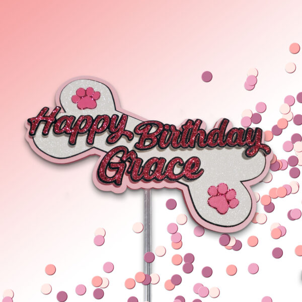 Thumbnail of glittery dog bone birthday topper for Grace with paw prints and custom script text.