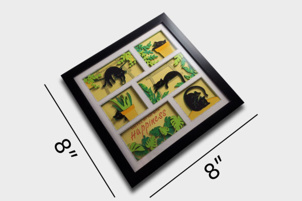 Angled view of a 3D paper shadow box revealing multiple layers of playful black cats, vibrant leaves, and yellow pots. The black frame accentuates its dimensional design, showcasing curious felines and cheerful greenery for a bright, fun display Fun.
