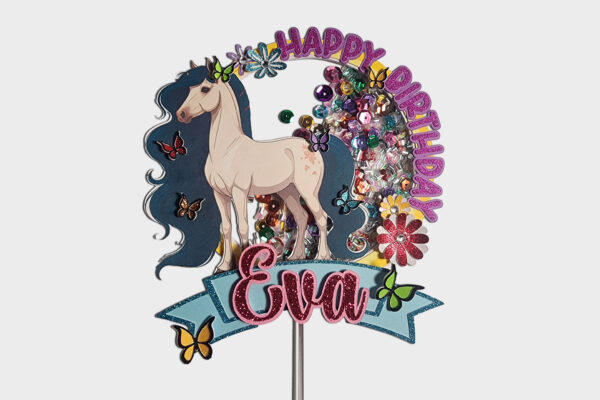 Straight shot of a whimsical horse-themed shaker cake topper for girls’ birthdays. It features a cream-colored horse with a flowing blue mane, a pink glitter ‘Happy Birthday’ arch, and the name ‘Eva’ in sparkly pink lettering. Colorful butterflies and flowers accent the design, while jewel-like confetti moves behind the transparent shaker layer. A clear acrylic stick extends beneath the 5.5-inch-wide topper.